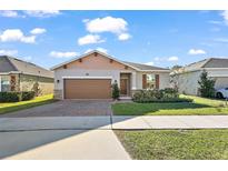 One-story home with brown garage door, landscaping, and brick pavers at 29549 Caspian St, Leesburg, FL 34748