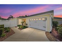 Front view of a yellow house with a two-car garage and landscaped yard at 1405 Conchas Dr, The Villages, FL 32162