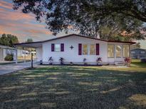 White single story home with carport, landscaping, and a spacious yard at 1611 Cherry Hill Rd, The Villages, FL 32159