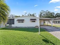 Single-wide manufactured home with carport and well-maintained lawn at 712 Tarrson Blvd, The Villages, FL 32159