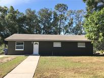 Newly renovated house with a dark brown exterior, white door, and walkway at 11 The Crescent, Minneola, FL 34715
