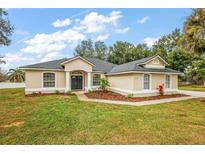 One-story home with landscaped yard, dark gray roof, and two-car driveway at 14701 Timucua Pl, Clermont, FL 34711