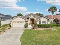 One-story house with beige exterior, two-car garage, and manicured lawn at 1589 Arial Pl, The Villages, FL 32162