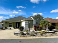 Green house with gray roof, landscaped yard, and driveway at 3462 Allison Pl, The Villages, FL 32163