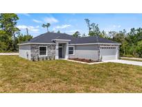 Single-story home with gray siding, stone accents, and a two-car garage at 40630 E Eighth Ave, Umatilla, FL 32784