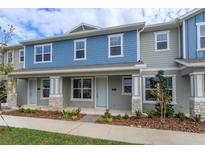 Two-story townhome with blue and gray siding, stone accents, and a front porch at 16436 Hamlin View St, Winter Garden, FL 34787