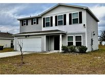 Two-story house with gray siding, black shutters, and a white garage door at 209 Hyacinth Ct, Kissimmee, FL 34759