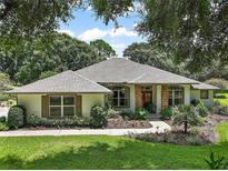 One-story home with gray roof,red door,landscaped yard, and walkway at 6147 Spinnaker Loop, Lady Lake, FL 32159