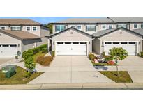 Front view of townhome with two-car garage and landscaped yard at 8512 Magnificent Ln, Groveland, FL 34736