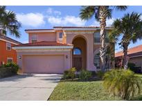 Two-story house with a pink facade, a three-car garage, and lush landscaping at 151 Rubino Dr, Davenport, FL 33837