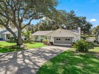 White single-story home with a garage and landscaped lawn at 1310 Moray Ct, Leesburg, FL 34788