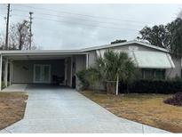 Mobile home with carport, covered walkway and landscaped yard at 1335 E Schwartz Blvd, Lady Lake, FL 32159