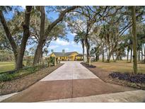 Charming yellow home with a large driveway and mature trees at 606 N Shore Dr, Leesburg, FL 34748