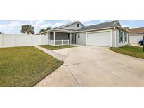 View of backyard with grassy area, white fence, and a concrete driveway at 4056 Venetian Ln, The Villages, FL 32163