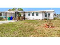 White single-wide mobile home with carport, ramp, and landscaped yard at 1559 Nassau Cir, Tavares, FL 32778