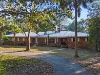 Brick ranch home with metal roof, long driveway, and mature landscaping at 22740 County Road 44A, Eustis, FL 32736