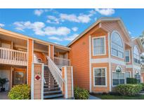 Exterior view of a two-story building with orange siding and a staircase at 3141 Britannia Blvd # D, Kissimmee, FL 34747