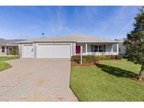 Single-story home with gray siding, two-car garage, and landscaped yard at 3447 Ridgewood Path, The Villages, FL 32163