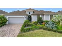 One-story home with gray exterior, landscaped yard, and paver driveway at 558 Timbervale Trl, Clermont, FL 34715