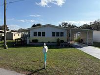 Single-wide manufactured home with carport and fenced yard at 975 Cr 461, Lake Panasoffkee, FL 33538