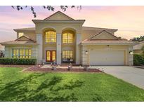 Stunning two-story house exterior illuminated at dusk with manicured lawn and landscaping at 6607 Crestmont Glen, Windermere, FL 34786