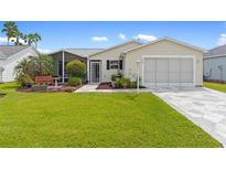 Cute Florida home with landscaped lawn, screened porch, and a paved driveway at 869 Aiken Ave, The Villages, FL 32162