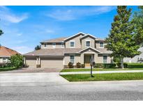Two-story house with a three-car garage and landscaped yard at 9249 Ivywood St, Clermont, FL 34711