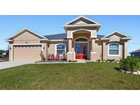 Single-story home with a red door, attached garage, and well-manicured lawn at 807 Lake Marie Dr, Dundee, FL 33838