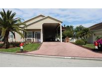 Tan house with carport and landscaped front yard at 337 Motorcoach S Dr, Polk City, FL 33868