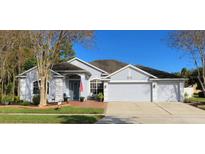 Two-story house with gray siding, a three-car garage, and a brick walkway at 141 Winghurst Blvd, Orlando, FL 32828