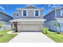 Two-story house with beige siding, a two-car garage, and landscaping at 1417 Leamington Ln, Winter Haven, FL 33884