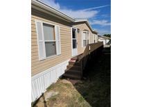 Tan mobile home with wooden deck and steps at 50989 Highway 27 # 230, Davenport, FL 33897