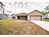 Newly constructed one-story home with a light brown exterior, two-car garage, and a spacious lawn at 3671 E Gaskins Rd, Bartow, FL 33830