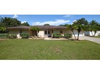 Tan single-story house with a large yard, double doors, and a white garage door at 2646 Handley Blvd, Lakeland, FL 33803
