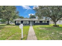 Ranch style home with dark blue exterior, white trim, and a landscaped lawn at 1206 Price Ave, Auburndale, FL 33823