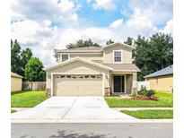 Two-story house with tan siding, two-car garage, and landscaping at 3926 Rollingsford Cir, Lakeland, FL 33810