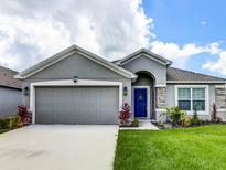 Gray house with a blue door, two-car garage, and landscaped lawn at 1949 Thompson Preserve Blvd, Bartow, FL 33830