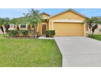 Tan house with two-car garage, palm trees, and well-maintained lawn at 834 Auburn Preserve Blvd, Auburndale, FL 33823