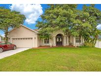 Tan house with a red car parked in the driveway at 2948 Vintage View Cir, Lakeland, FL 33812