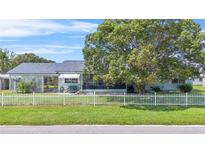 Light blue house with a white picket fence and large tree at 13958 Hatchineha Rd, Haines City, FL 33844
