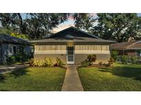 Tan Bungalow style home with a walkway, landscaping, and a well-maintained lawn at 1127 N Stella Ave, Lakeland, FL 33805