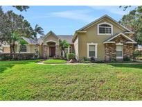 Tan two-story house with stone accents and manicured lawn at 109 Costa Loop, Auburndale, FL 33823