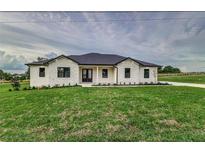 Stunning ranch home with white and stone exterior, a covered entry, and manicured lawn at 1001 Cody Bluffs Rd, Babson Park, FL 33827
