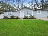 Newly renovated home with gray siding, green lawn, and palm trees at 5225 Golden Gate Blvd, Polk City, FL 33868