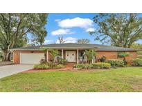 Brick ranch house with a covered porch, well-maintained landscaping, and a two-car garage at 4264 Stafford Dr, Winter Haven, FL 33880