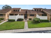 Tan two-story condo building with grassy landscaping and walkways at 5225 Imperial Lakes Blvd # 22, Mulberry, FL 33860