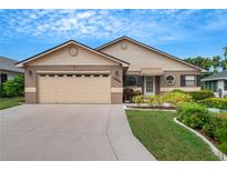 Beige house with two-car garage, landscaped lawn, and a walkway to the front door at 6256 Sandpipers Dr, Lakeland, FL 33809