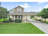 Two-story house with stone accents, covered porch, and landscaped yard at 4511 Micanope Crescent Dr, Lakeland, FL 33811