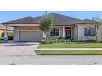 Tan house with brown roof, double garage, and lush landscaping at 1898 Charleston Ln, Bartow, FL 33830