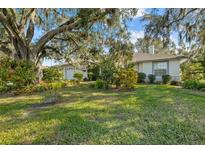 Spacious front yard with lush landscaping and mature oak tree at 150 Woodcrest Ln, Mulberry, FL 33860